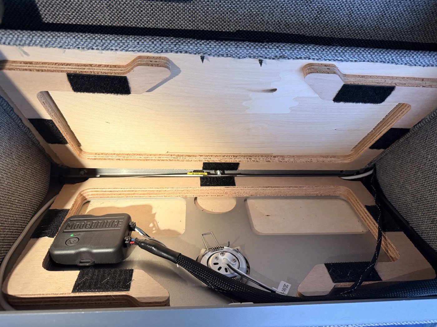 A ModeBRIDGE controller mounted inside a van's overhead cabinet, connected by its harness.